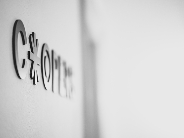 Coopers Executive Seitliches schwarz-weiss Foto, von dem Cooperslogo an einer Wand.