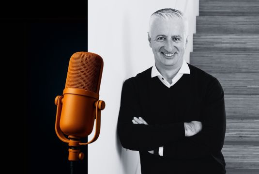 Portrait of Olivier Rihs, Board Member of Coopers Group, smiling with arms crossed next to a microphone.