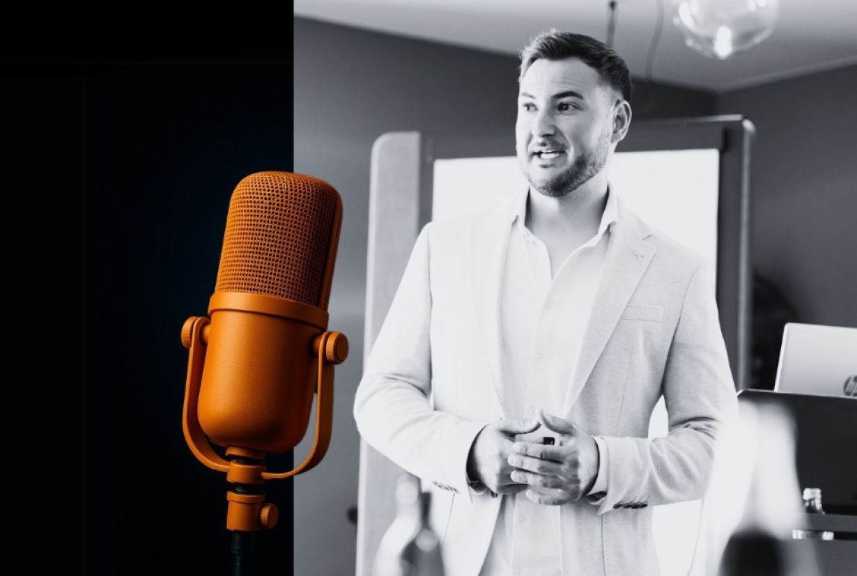 Philipp Kaufmann steht lächelnd in einem hellen Raum, im Vordergrund ein grosses Mikrofon.