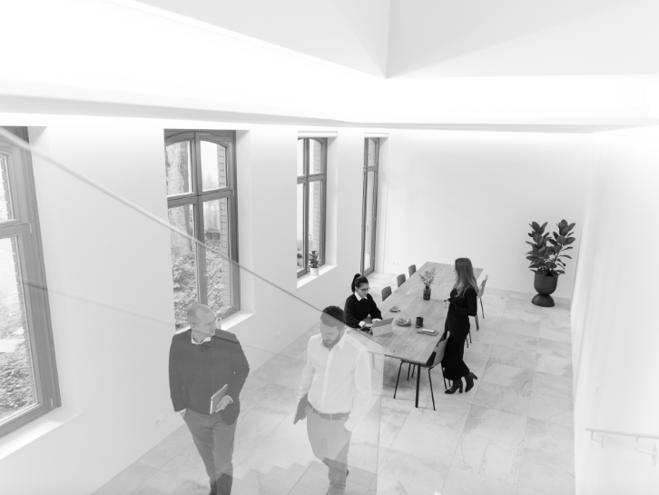 Coopers Family – Coopers Executive Bright room with large windows, two people are talking to each other, two others are in conversation at the table.