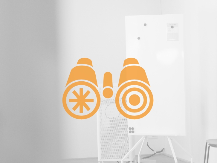 Coopers Executive Research & Market Intelligence Icon binoculars in the background bright room with flipchart.